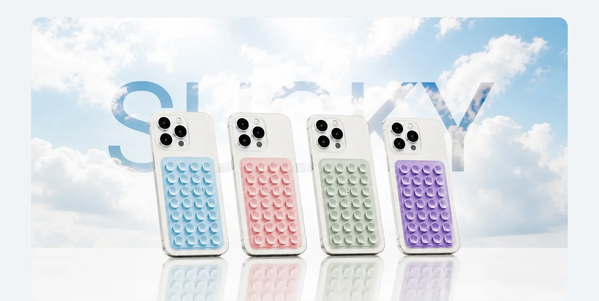 Sucky phone grips in blue, pink, green and purple lined up against clouds