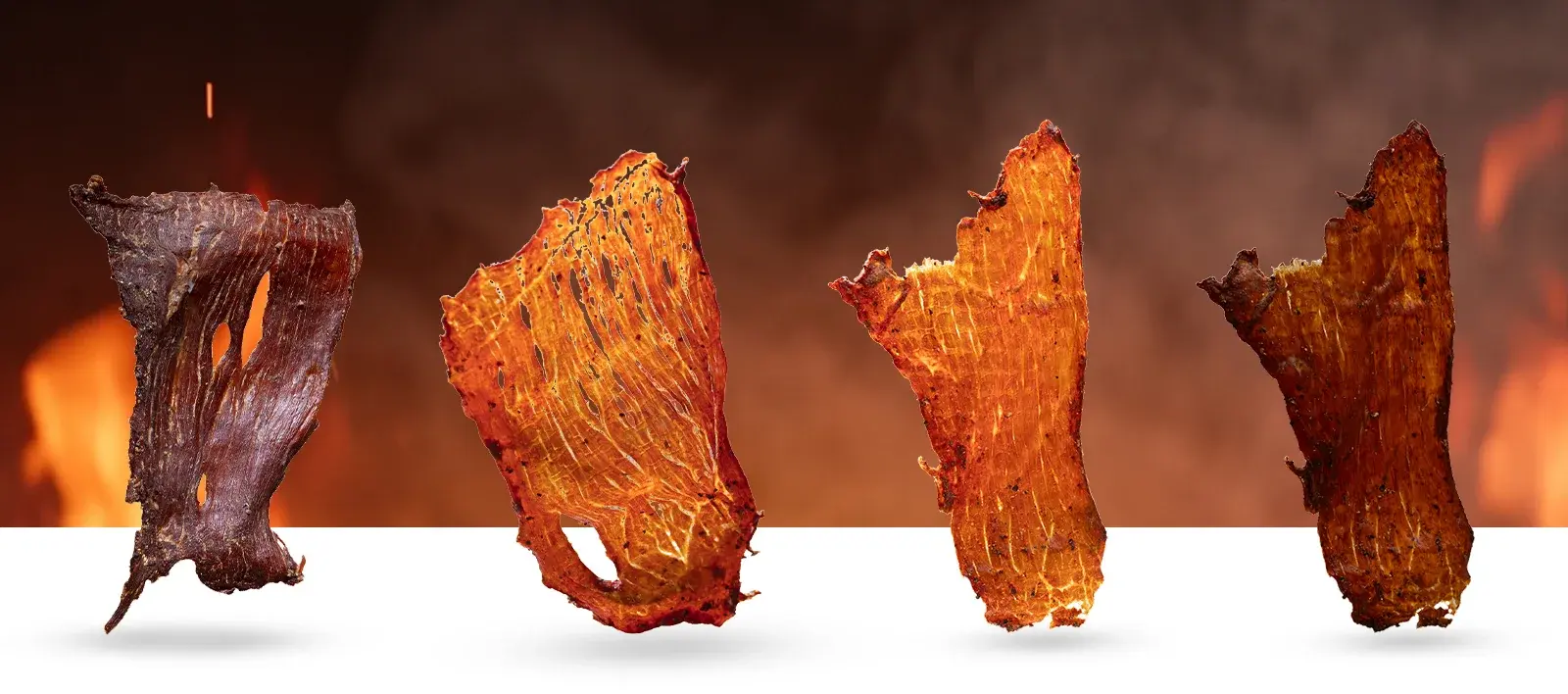 Four strips of beef jerky lined up against a fire backdrop